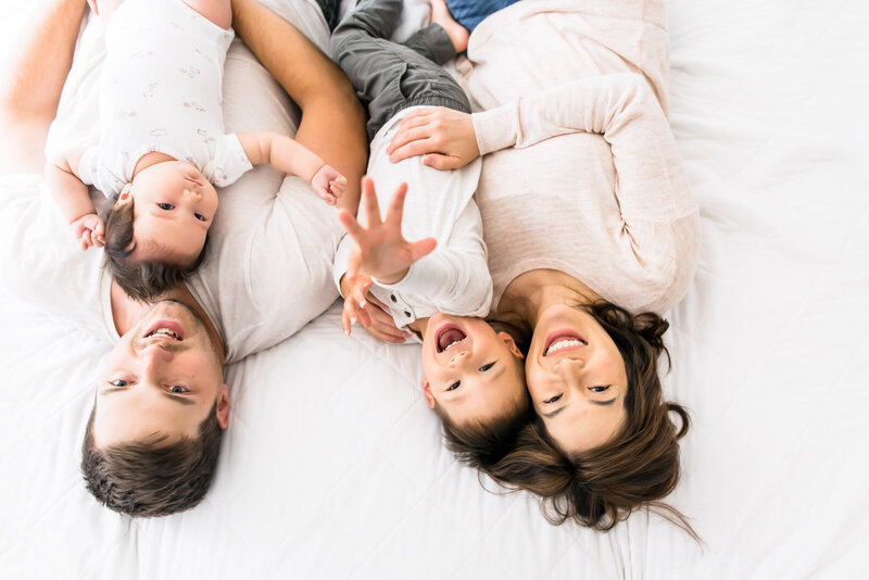 Woodinville family of four cuddles on bed for in home family session | Woodinville, WA