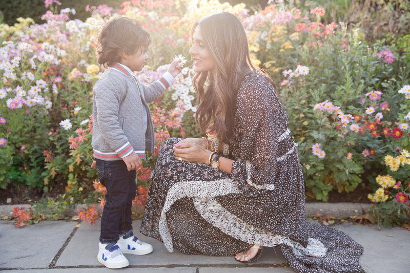 little boy hands mother a flower in Central Park Conservatory Gardens during NYC family photo shoot