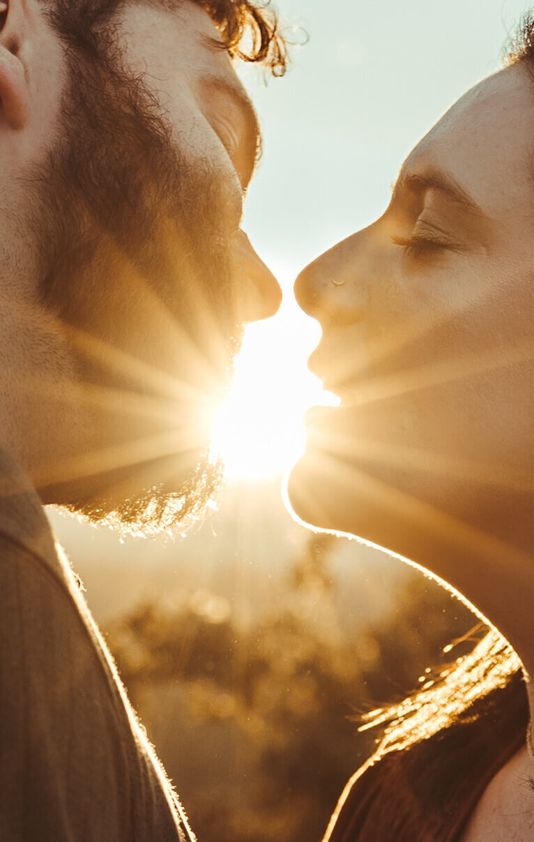 Silhouetted Couple Kissing With Sunburst Background