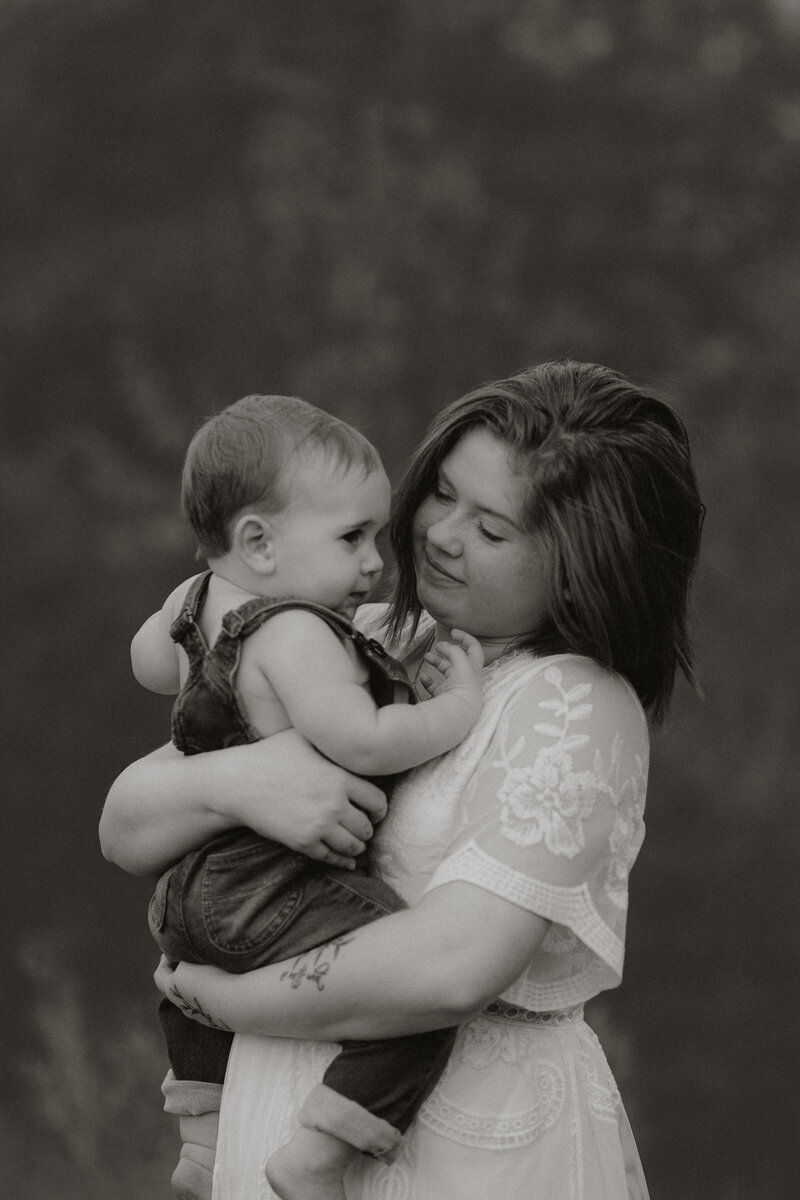 Mama in white dress carrying baby boy in blue overalls by Atlanta Motherhood Photographer.