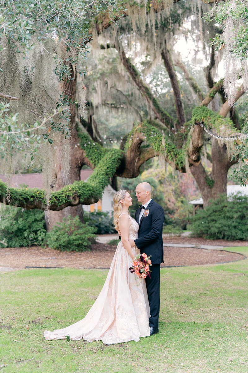 Pale pink jewel toned intimate Charleston fall elopement. Bride and groom under the lush greenery of live oak trees.