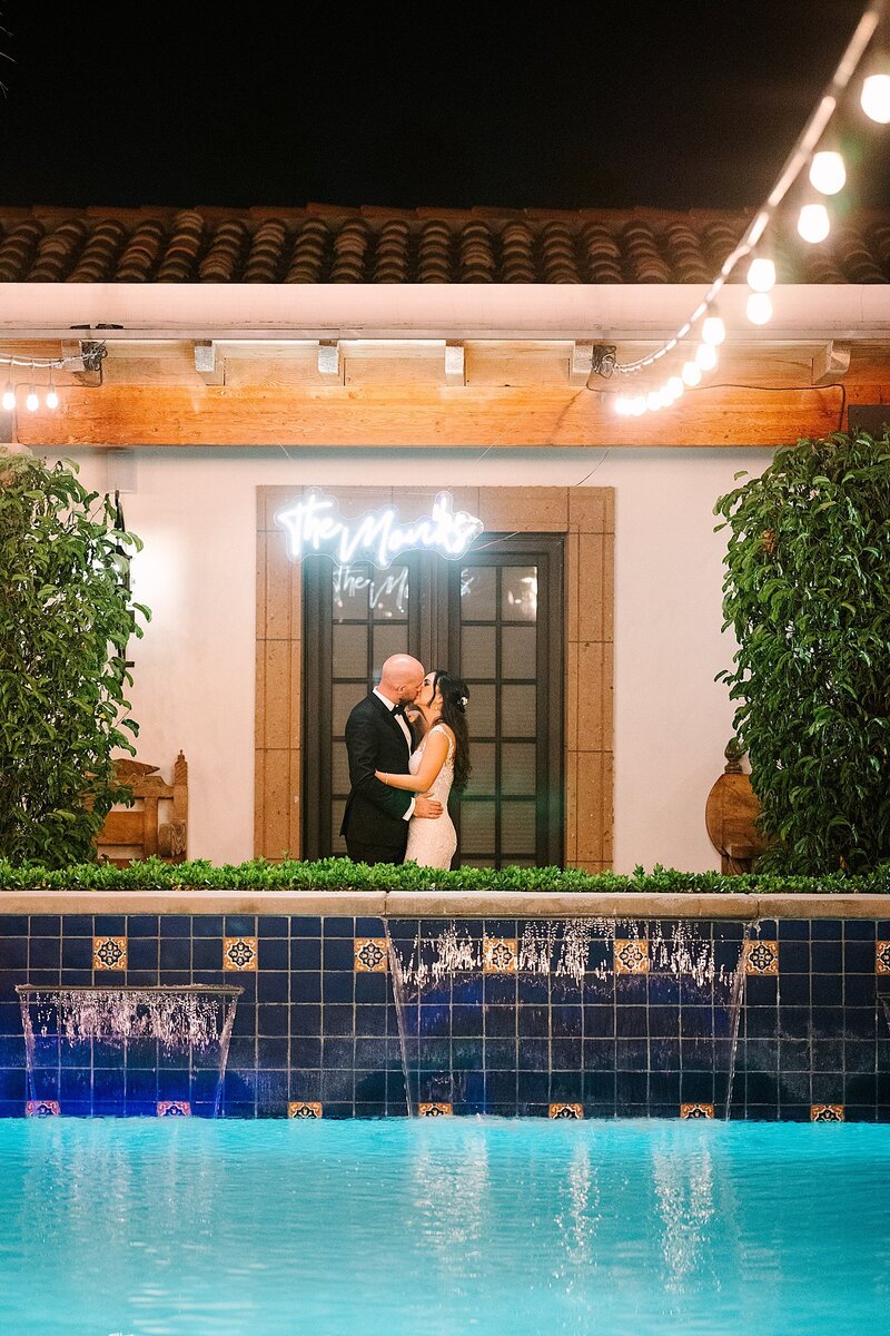 Bride and groom kissing under neon sign at Bougainvillea Estate wedding