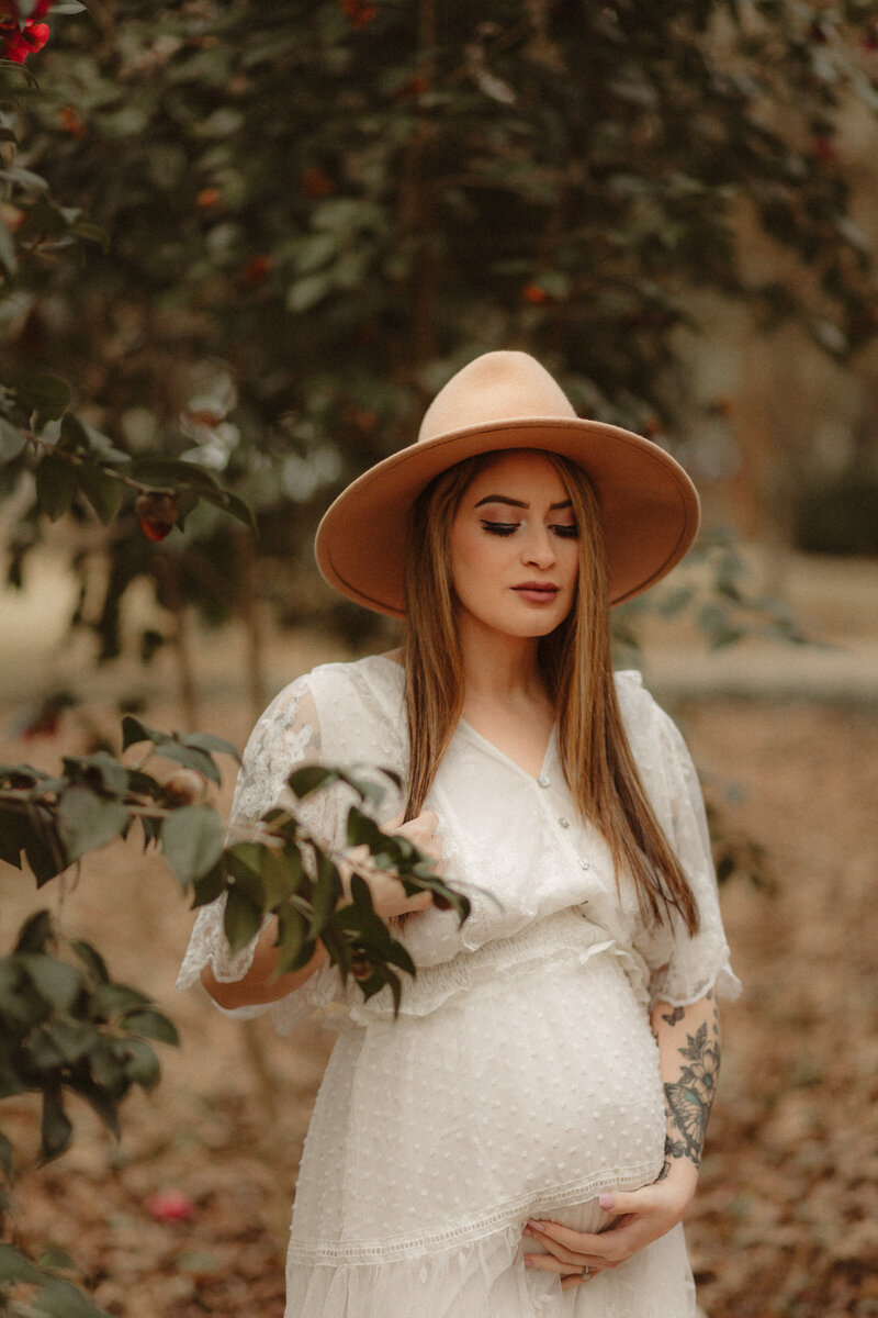 Maternity pictures in white dress with a hat by Atlanta Maternity Photographer.