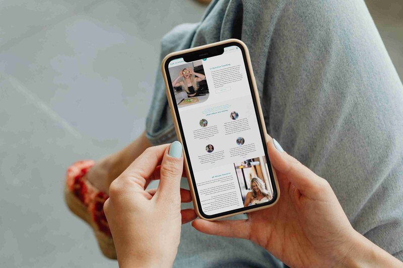 A woman's hands holding a smartphone displaying the Zoe Schroeder Nutrition website, showcasing healthy lifestyle tips.