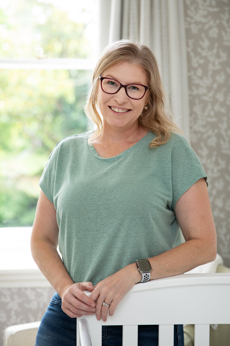 Sleep coach portrait posing at foot of cot in client's home in Christchurch