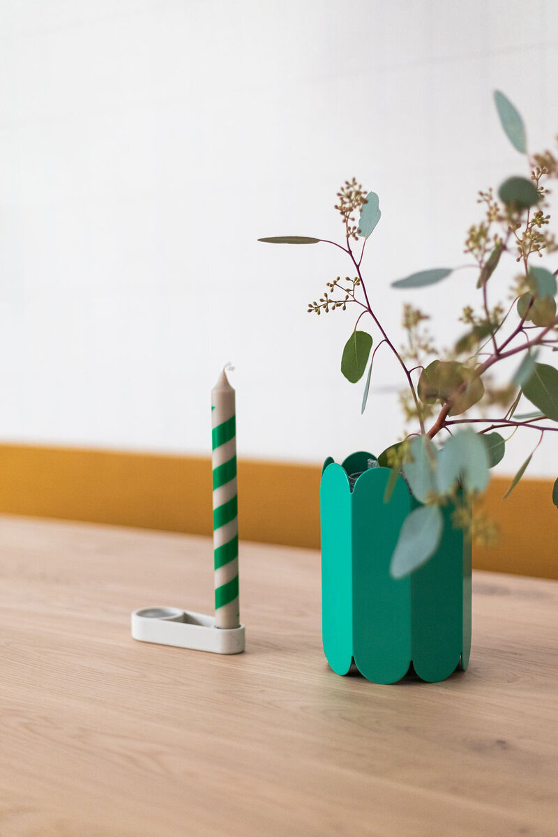 groene vaas met tak op eettafel