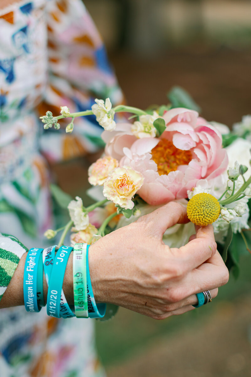 Woman wearing bracelets touching flowers