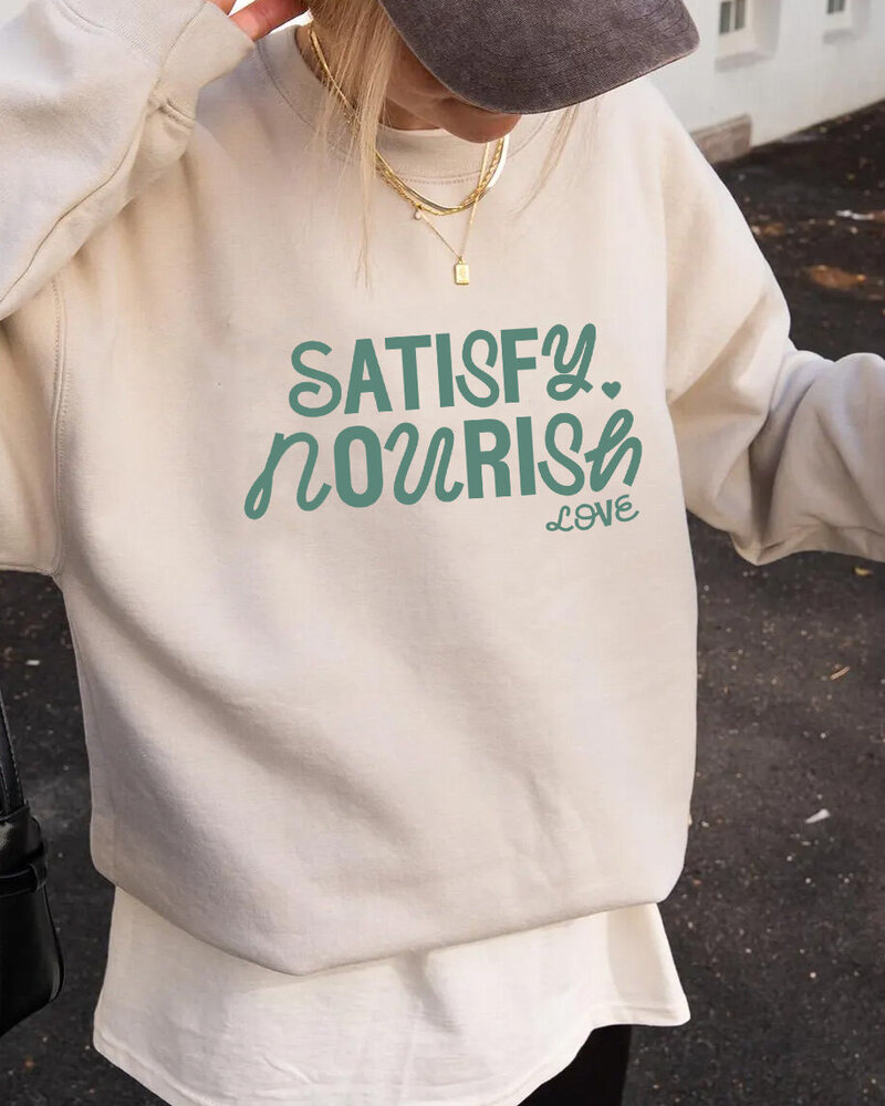 Sweatshirt featuring the phrases "satisfy," "nourish," and "love" in a stylish, uplifting design.
