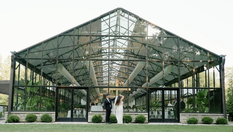 Groom twirls bride outside the Conservatory at Evergreen in Indiana