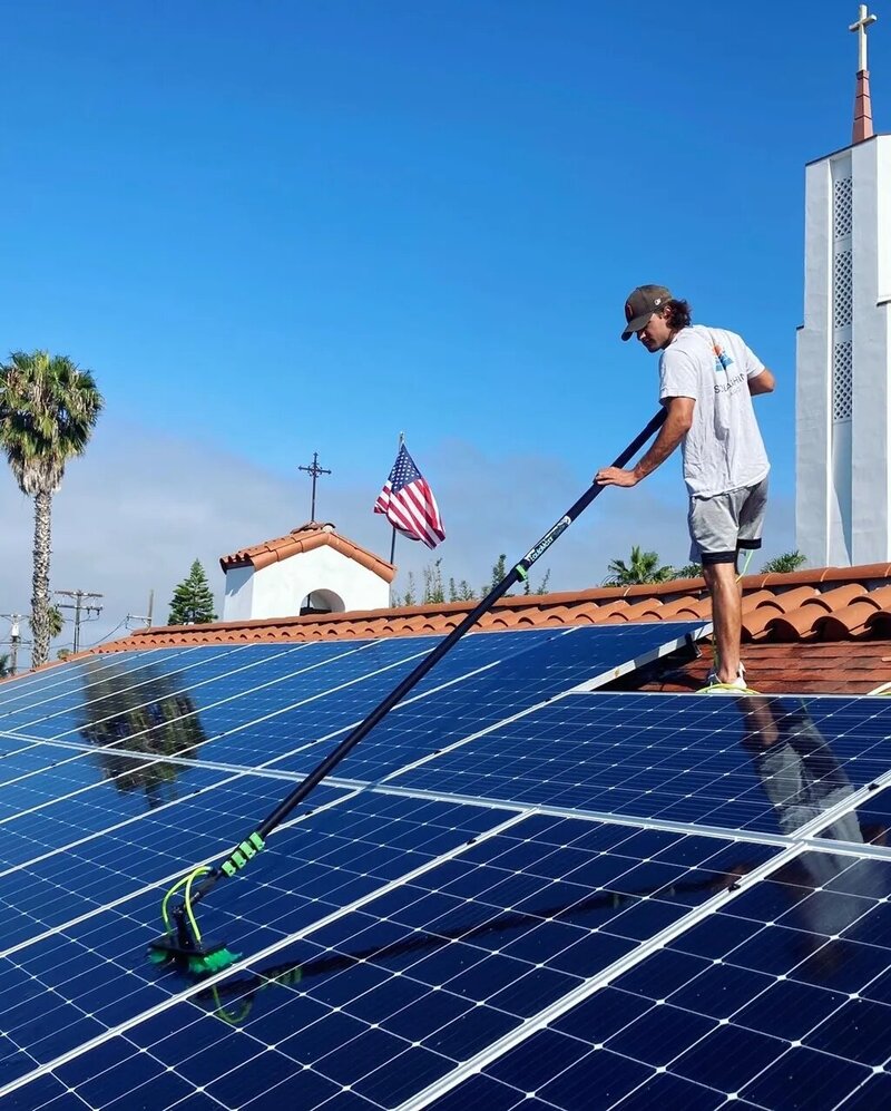Solar Shine SD technician using professional tools to clean solar panels on a roof, ensuring optimal energy efficiency and performance.