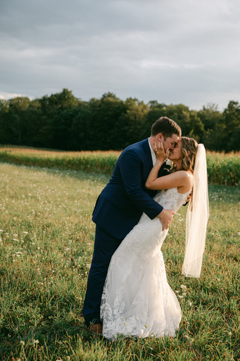 bride-groom-dip-kiss-meadow-sunset
