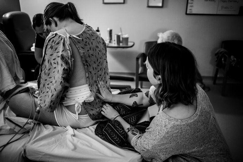 Black and white photo of a doula rubbing the back of a woman in labor