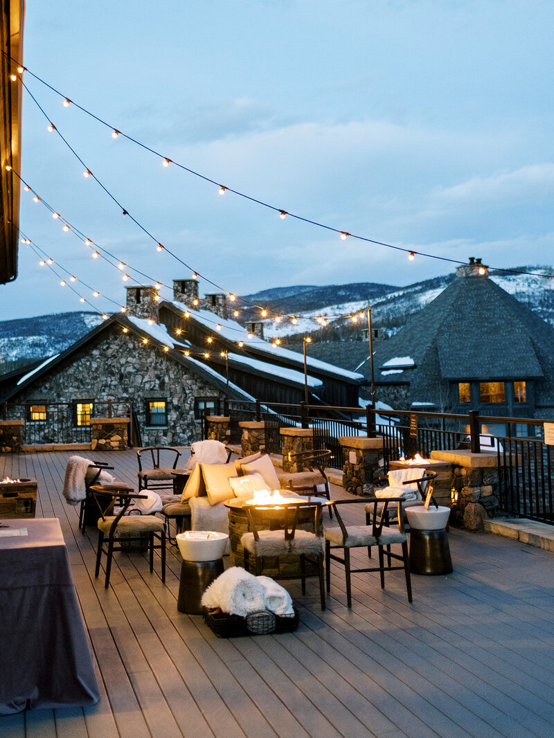 Casual outdoor winter-wedding patio space. There is a fire fit, and cozy seats, in the background there are mountains.