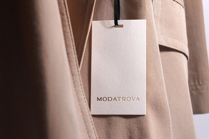 Goldfoil Modatrova logo on cream apparel tag on blush canvas wrap coat