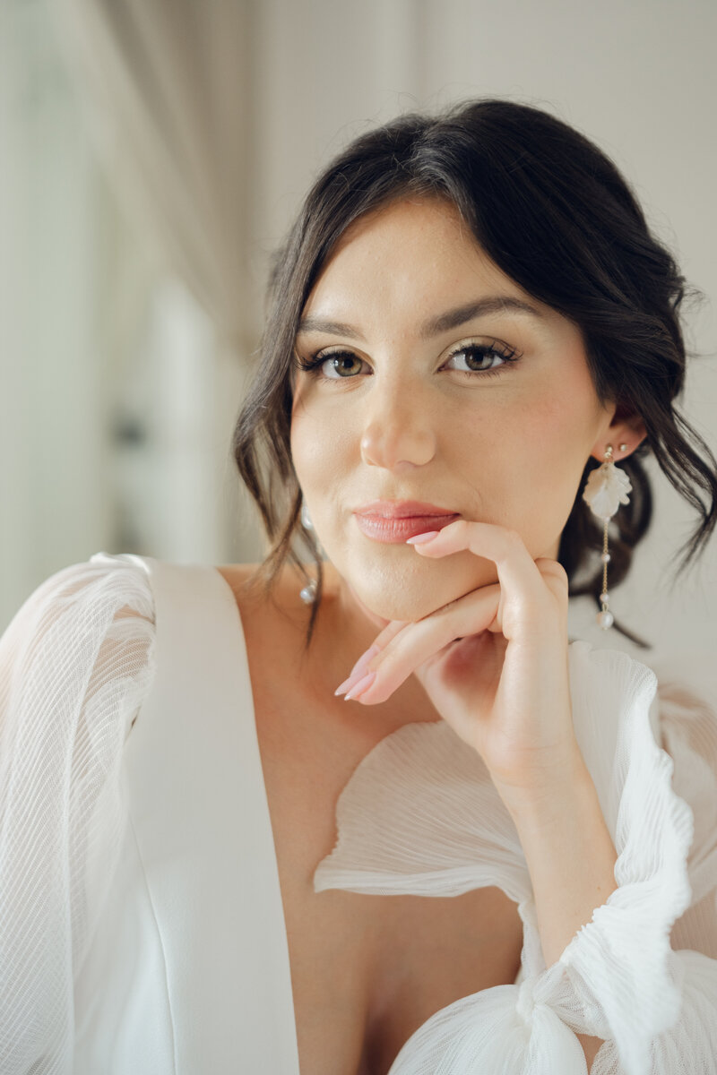 bride looking at the camera in a wedding dress resting her hand on her chin