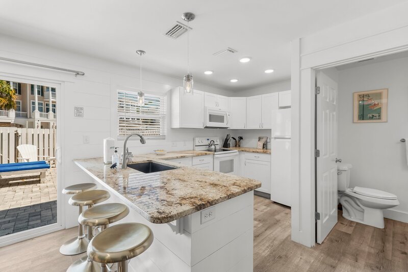 Spacious kitchen layout with island seating and access to patio at Tropical House, a top pick for 30A vacation rentals with personality.