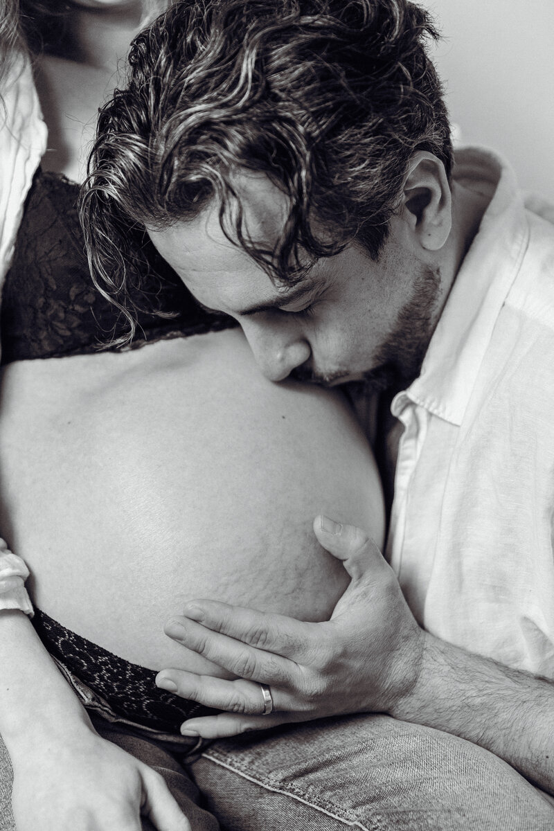 soon to be father holding pregnant wife's belly in maternity portrait