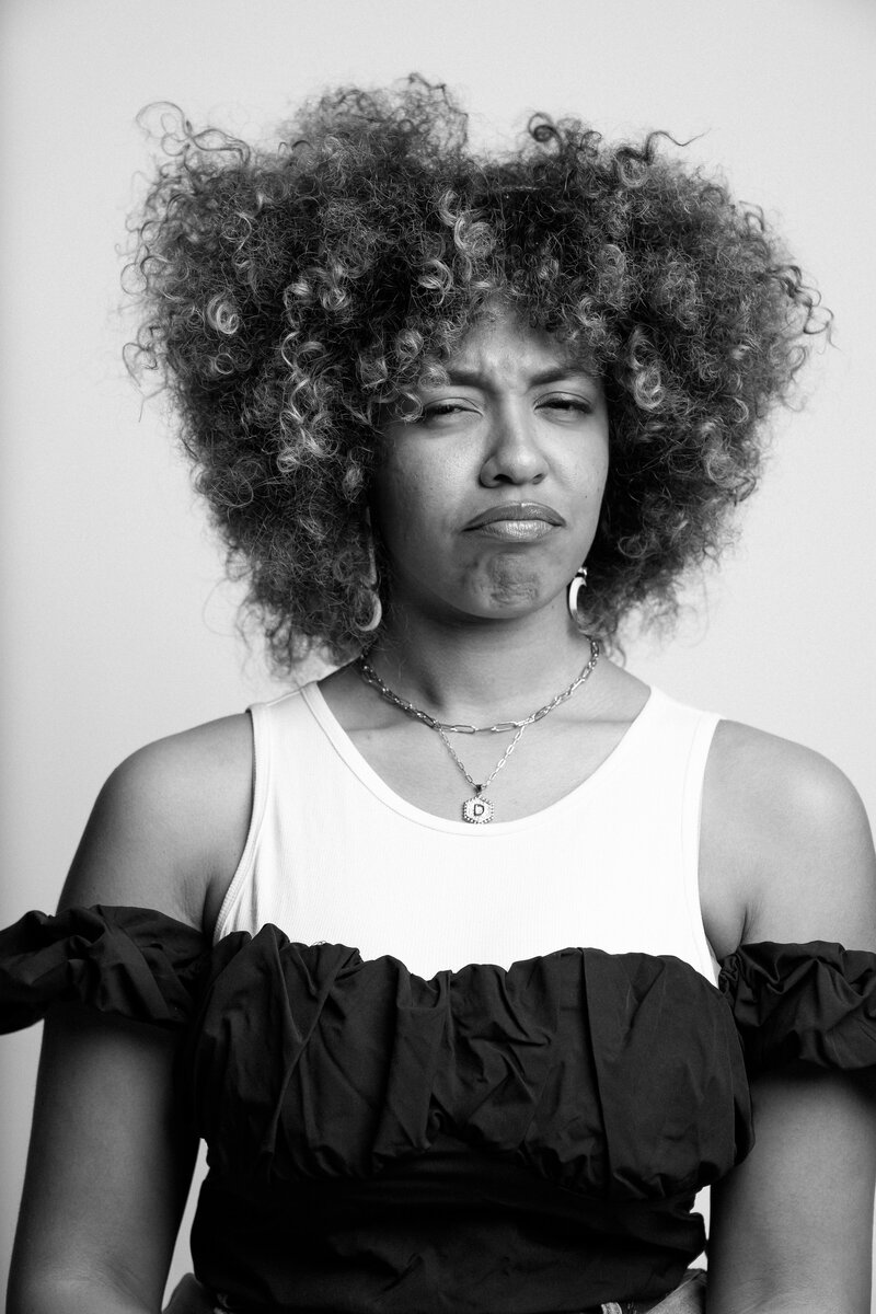 Black and white portrait with woman that is raw and unedited. Woman is making a humorous face. Part of Matt D Photography's "As I Am" series.