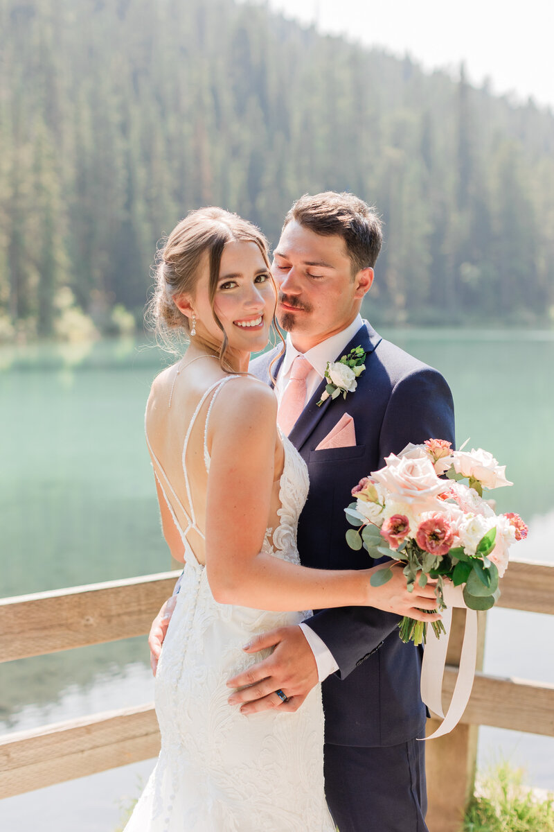 Couple with their arms around each other laughing and walking on a beach