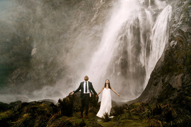 Couple standing in a waterfall New Zealand