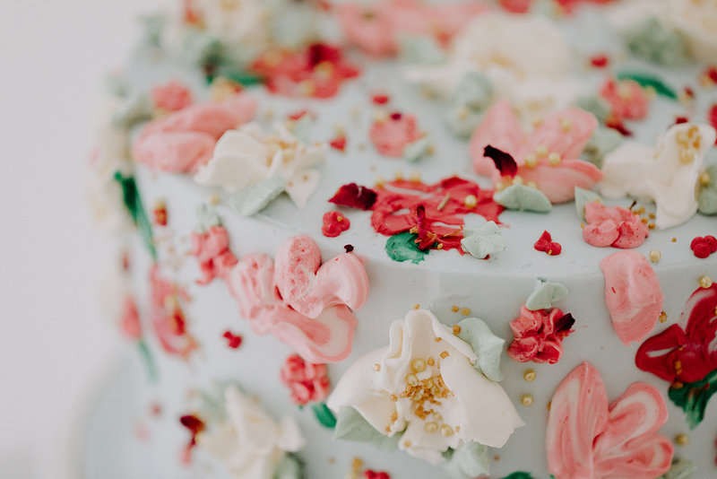 Close up of a light blue, pink, and white buttercream floral cake by Layered Cake Artistry