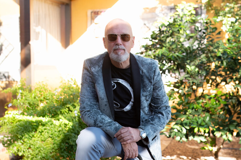 Man wearing sunglasses and a patterned blazer seated in a bright outdoor setting, photographed by Vyrl Photo, showcasing Tucson brand photography.