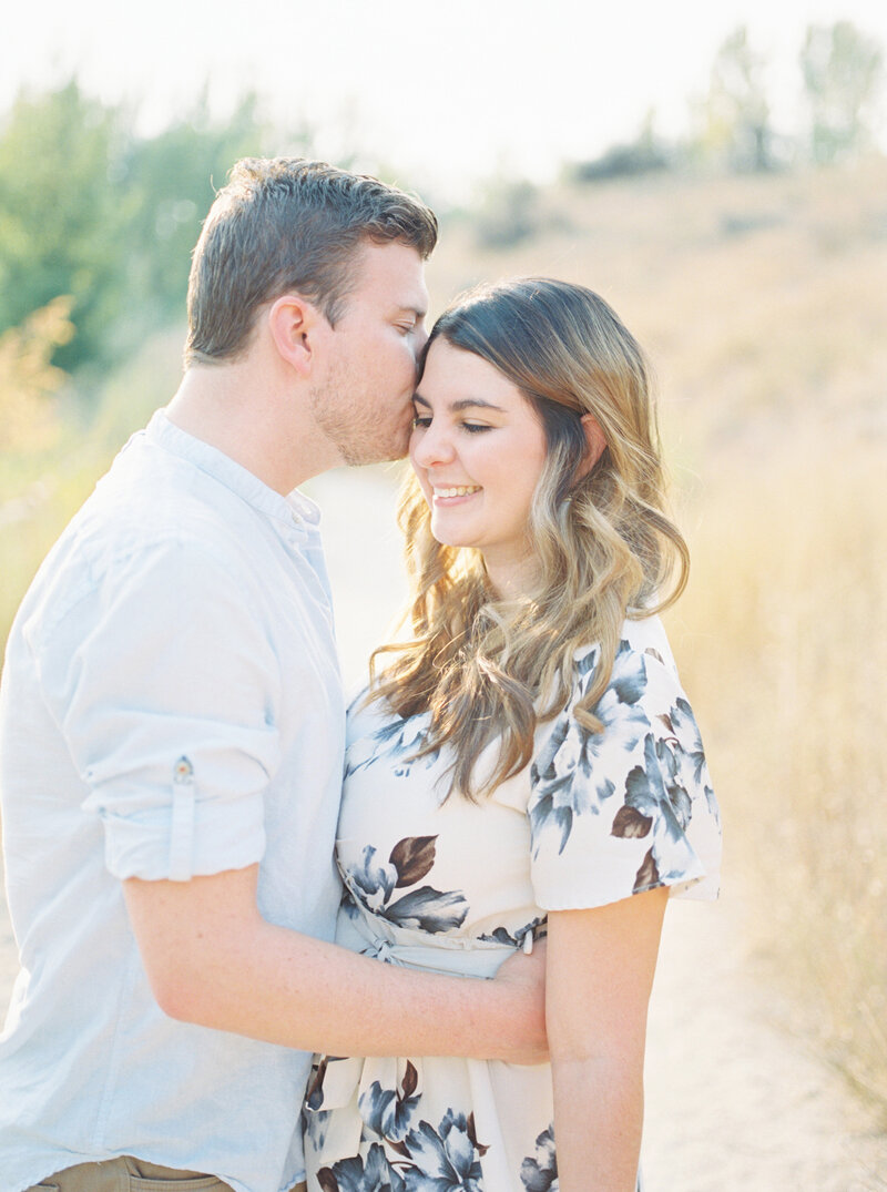 Man holding woman and kissing her forehead