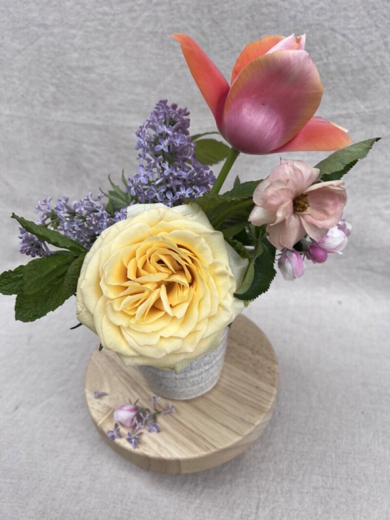 Spring flowers arranged in a petite ceramic bud vase, representing a Mother's day design by Wild Child Flower Co. 