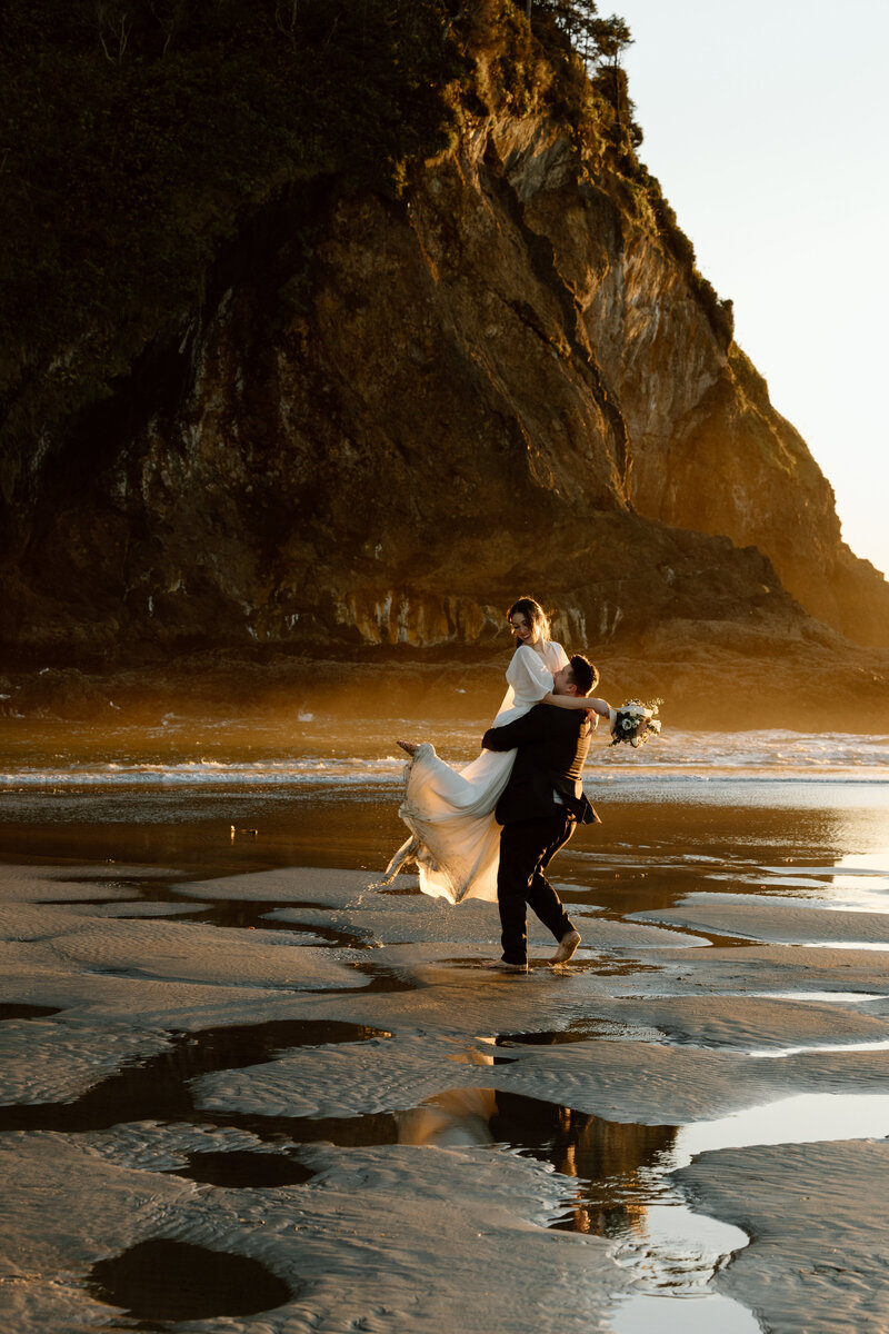 Groom lifting and swinging bride in circles on the Oregon Coast.