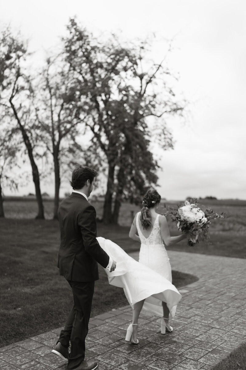 Black and white photo of a bride and groom dancing together outdoors, captured by Jessica from Rainstorm Photo & Video with a cinematic and nostalgic feel.