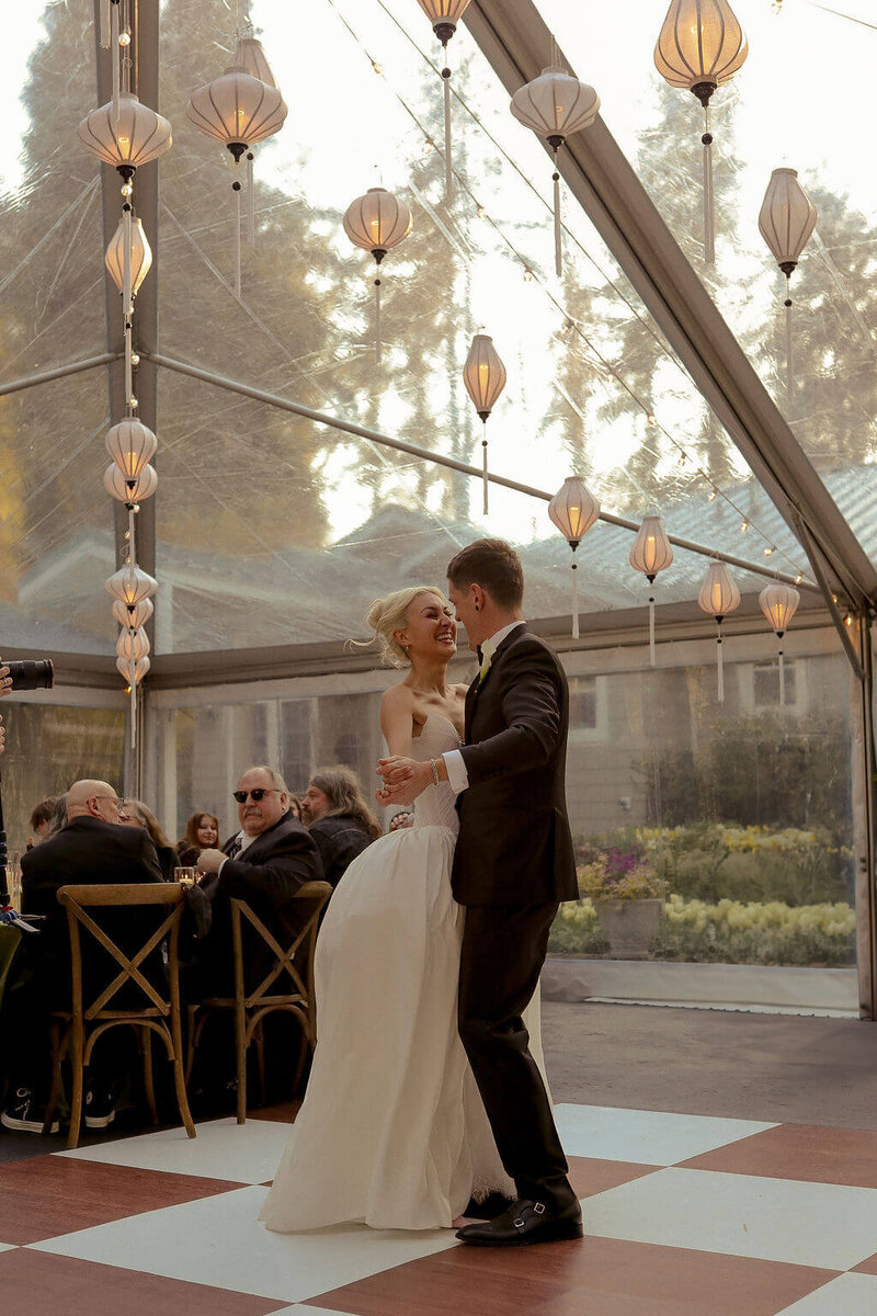 A bride and groom dancing in a tent with lanterns, representing examples of wedding decorations to rent for Oregon party rentals. 