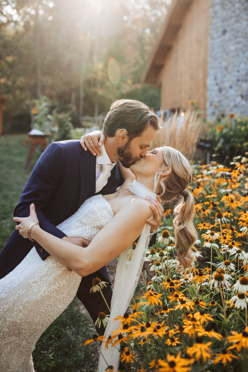 A groom dipping and kissing his bride over a bed of wildflowers in vermont. 