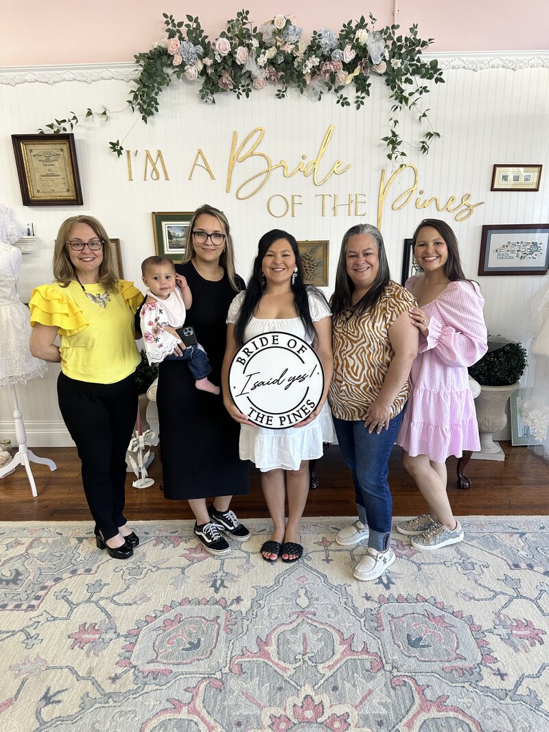 bride holding she said yes sign after finding wedding dress