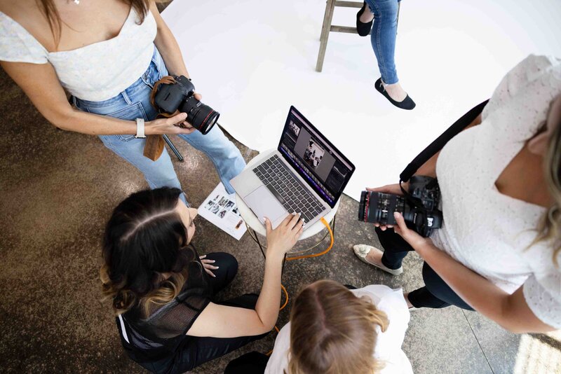 Aerial view of photography team reviewing images on laptop during brand photoshoot, showing collaborative creative process and professional equipment