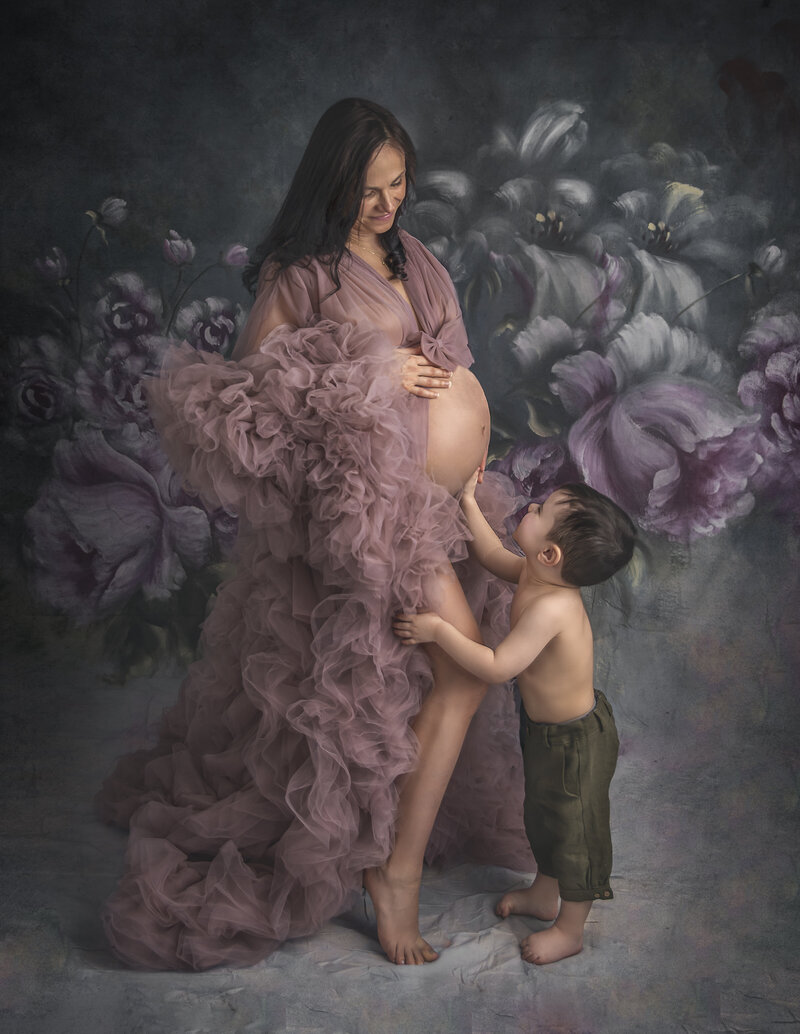 "A tender maternity portrait featuring a son lovingly kissing his mom's baby bump, captured in a heartwarming and intimate photography session in Ottawa."