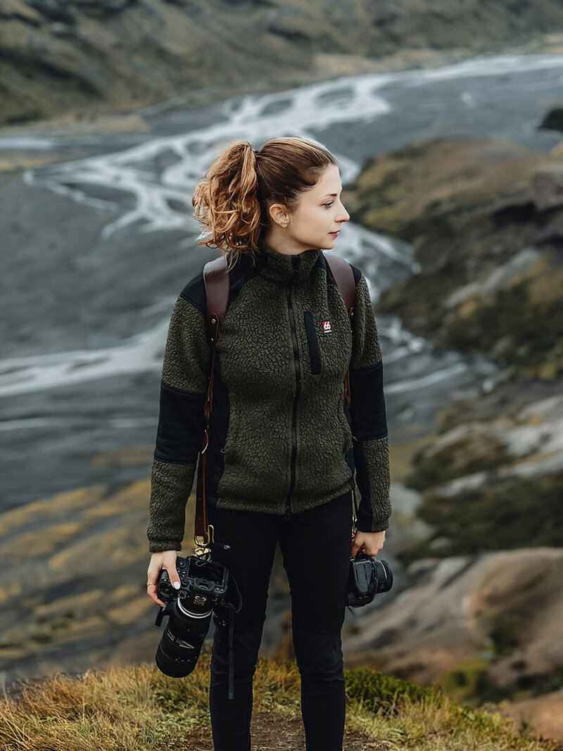 Local Iceland Elopement Photographer is standing with her two Canon cameras in Iceland's nature