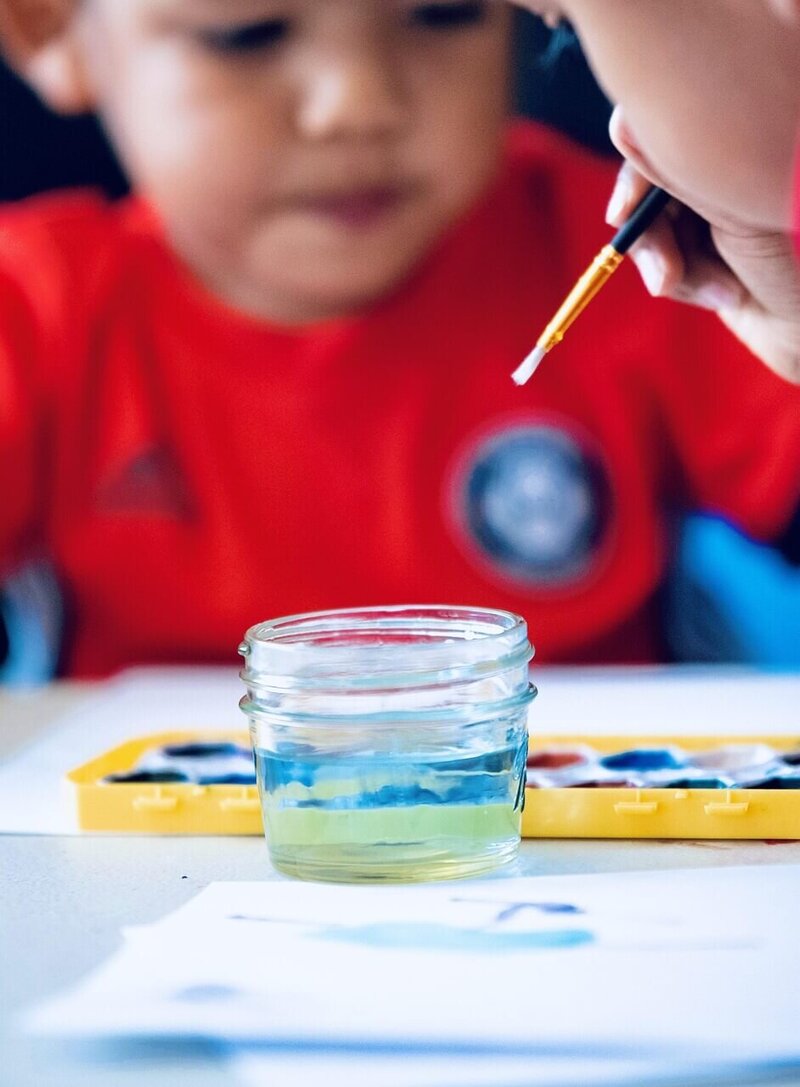 close up of paint brush about to dip in water