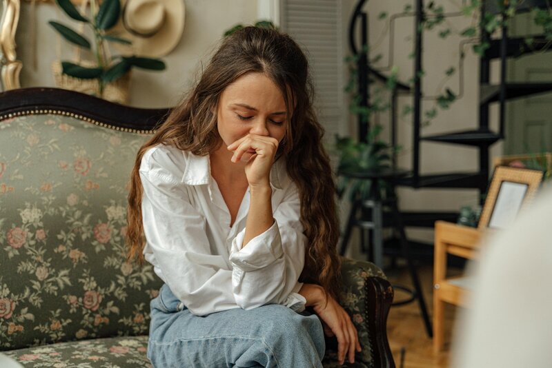 A brunette woman resting her head on her hand, looking overwhelmed—symbolizing the weight of anxiety and the path to relief through therapy.