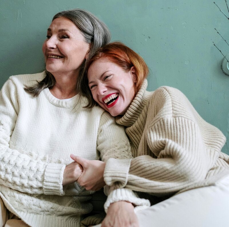 Mother and daughter leaning on each other while laughing.