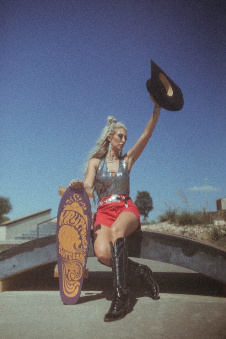 Model holds skateboard and cowboy hat