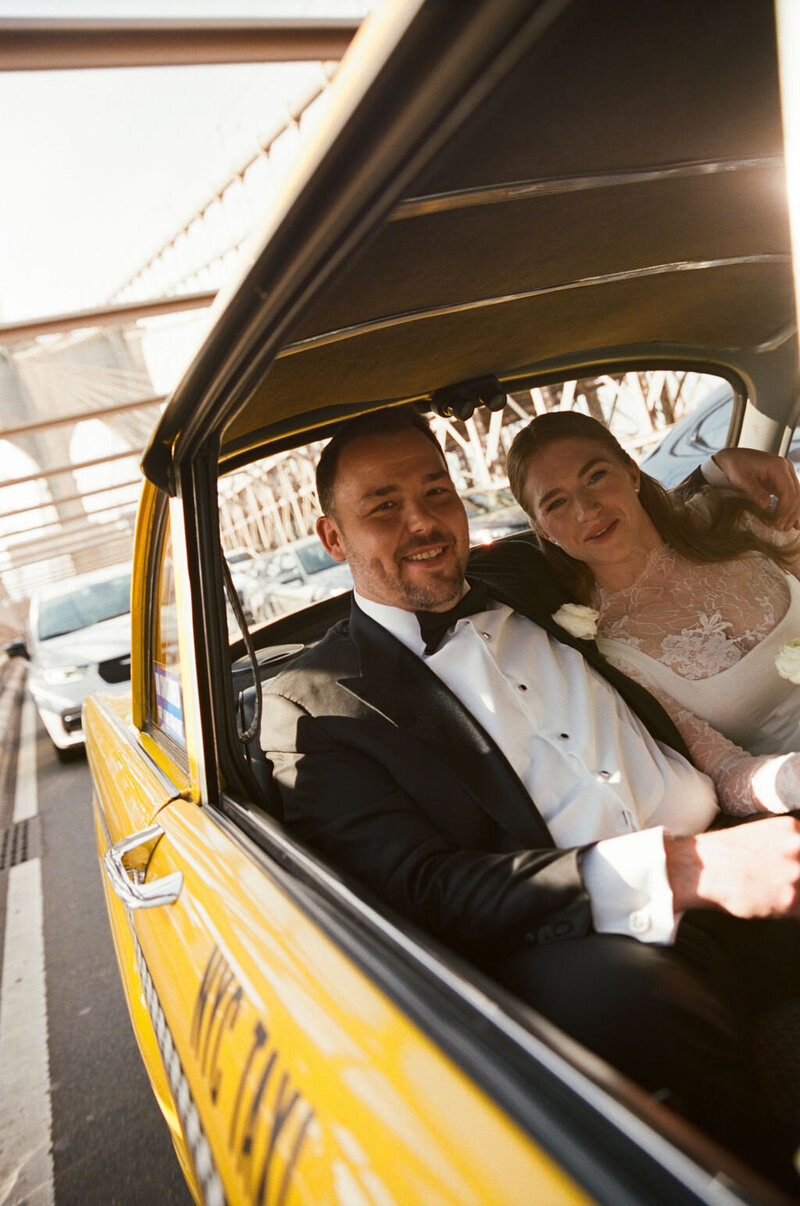 Carley and Shane smiling in the back of a yellow taxi