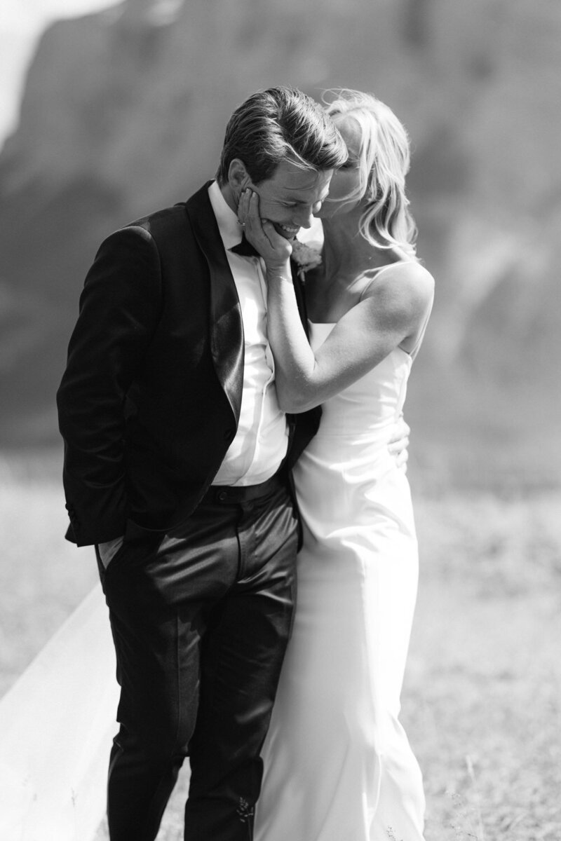 This stunning photograph captures the bride holding the groom’s face in a loving and luxurious manner as they walk together in Banff National Park. With the majestic Mount Rundle in the background, the image exudes elegance and romance, highlighting the beauty of their special day.