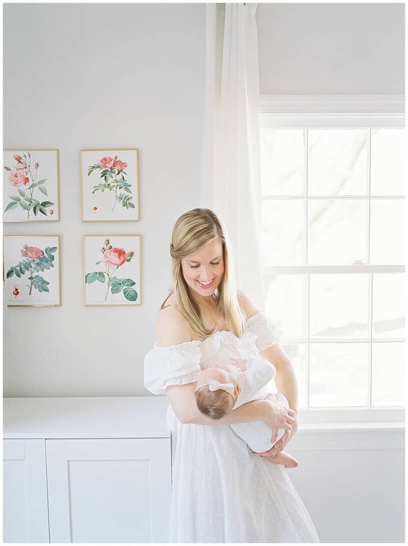 Family photographer DC Marie Elizabeth Photography holds her baby in the nursery