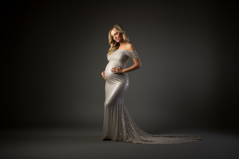 Maternity Beautiful mama  holding her belly looking down smiling softly