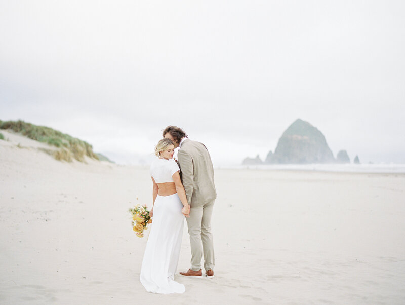 bride and groom kissing on the beach in front of Haystack Rock in Cannon Beach