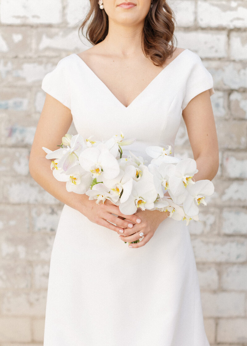 Bride in white holds orchid bridal bouquet