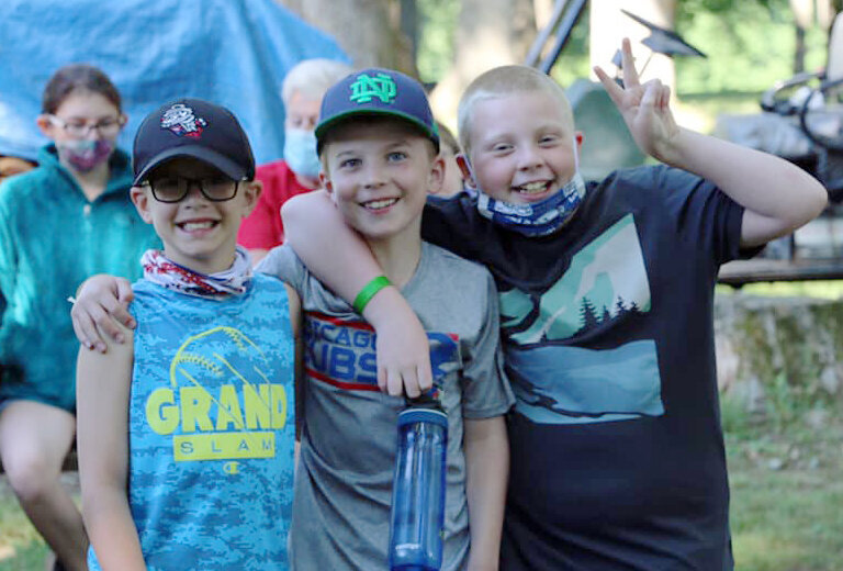 Three boys pose for a photo at summer camp.
