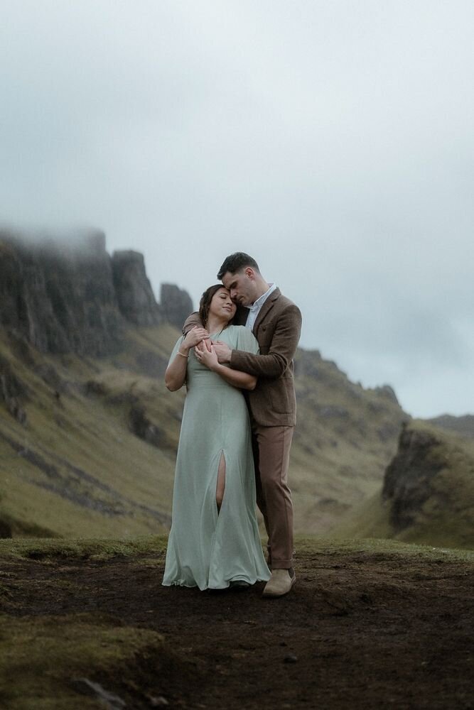 Couple hold each other close on a mountain on a moody day on the Isle of Skye, Scotland
