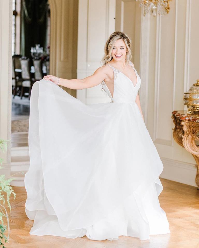Bride with hair down and curled twirls while holding her wedding gown, South Bend hair and makeup artists