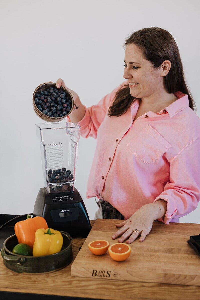 woman pouring fruit into blender